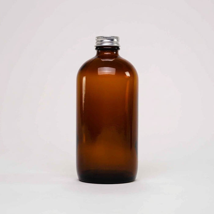 Rustic Strength, An empty 16oz amber glass bottle with a silver metal screw cap, centered against a plain light gray background.