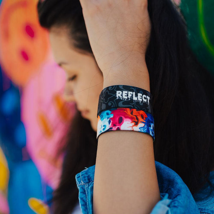 Young adult woman wearing two reflect ZOX with hand close to head. One ZOX shows the inside while the other shows the outside