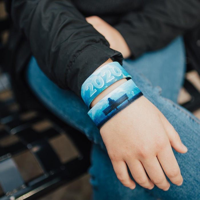 Modeled picture of 2020: hand wearing 2020 resting on the models leg while sitting on a park bench