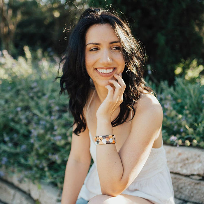 Lifestyle image of woman sitting on a bench smiling wearing Against the Grain