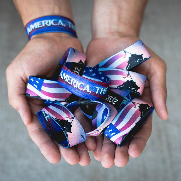 Lifestyle image of hands cupped together holding several America, The Free with one on their wrist
