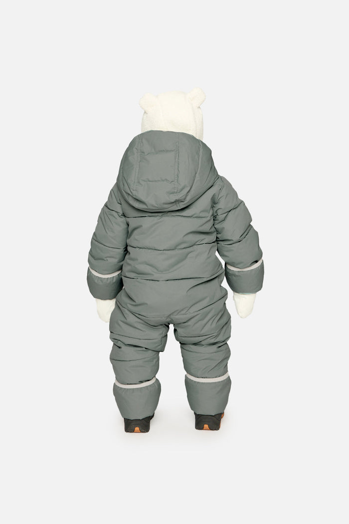 Back view of a baby standing in the sage green Deux par Deux Baby Cloud snowsuit