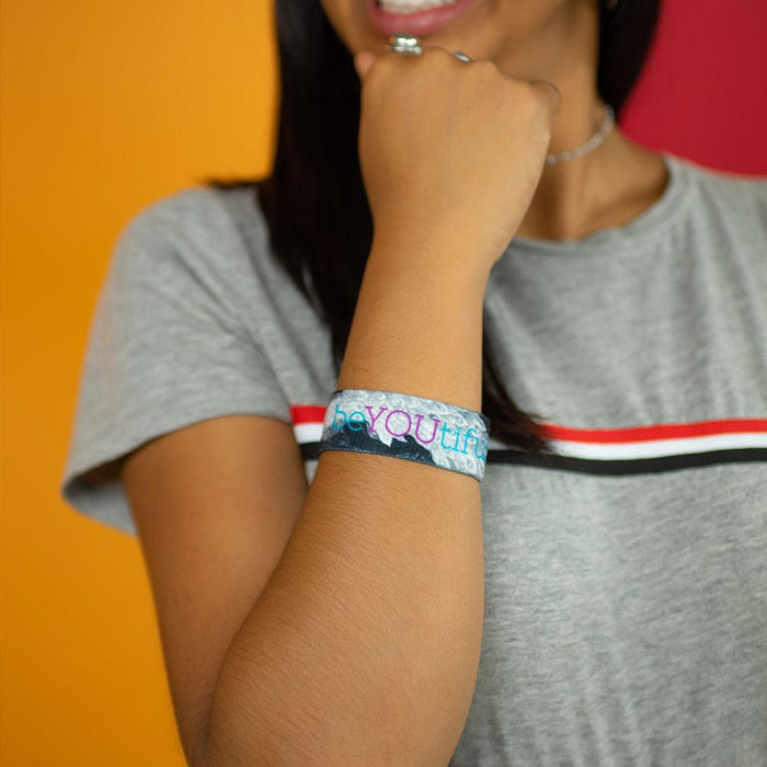 Studio Image close up of BeYOUtiful on woman's wrist while they are in a thinking pose