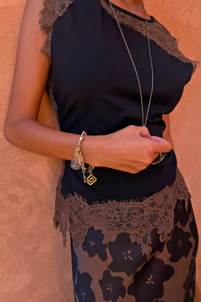 Black jersey top with chocolate lace trim and gold charm jewellery, featuring lace detail at the neckline and hem.
