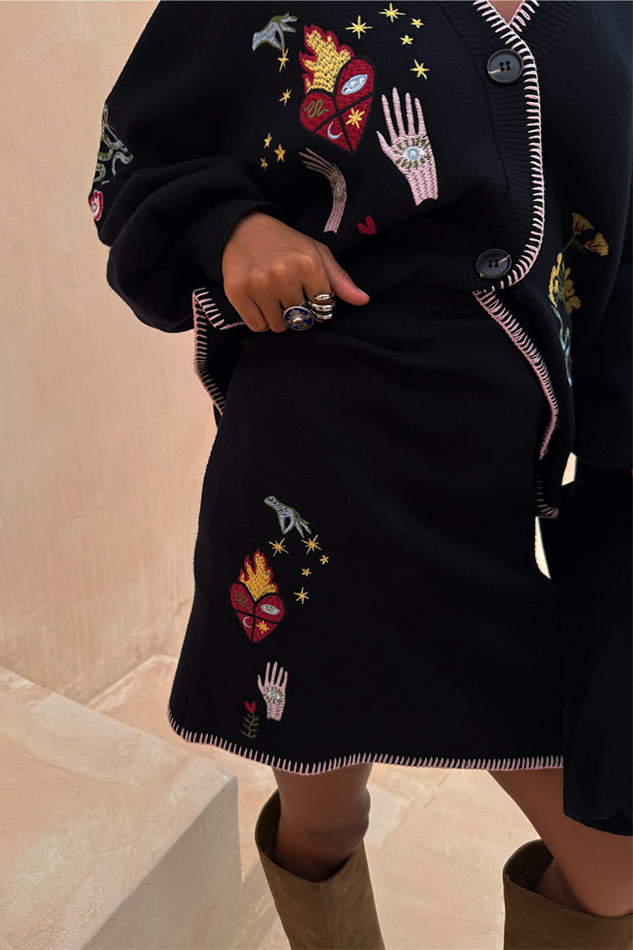 Black Night Garden Mini Wrap Skirt with pink blanket stitch detailing and mystical embroidery in a knit.