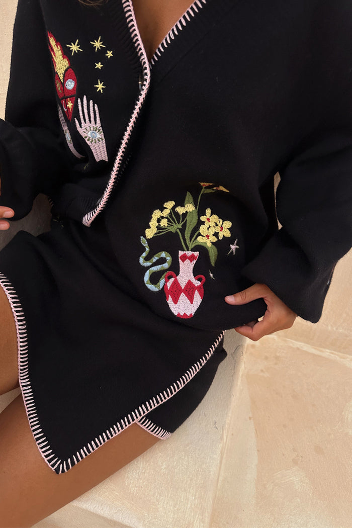 Black Night Garden Mini Wrap Skirt with pink blanket stitching and mystical motifs, styled as a soft knit co-ord.