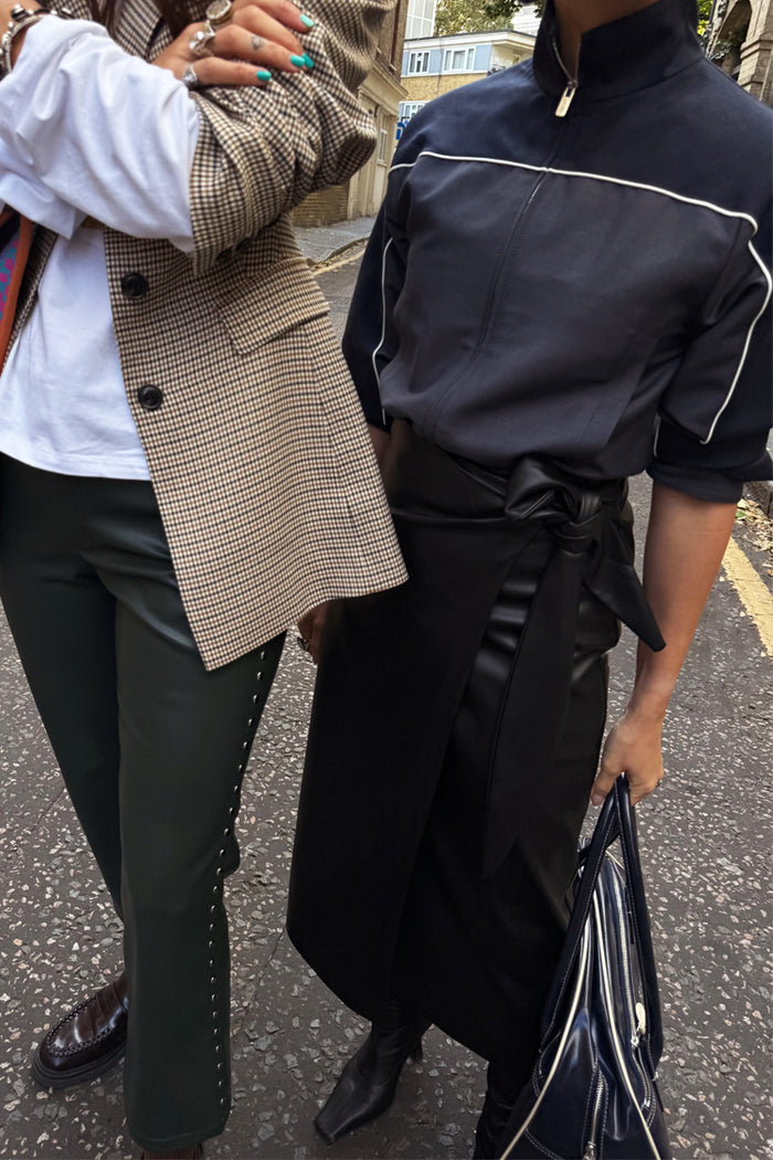 Iconic Black Vegan Leather Jaspre Wrap Skirt with a tulip shaped tie, styled for a London street look.