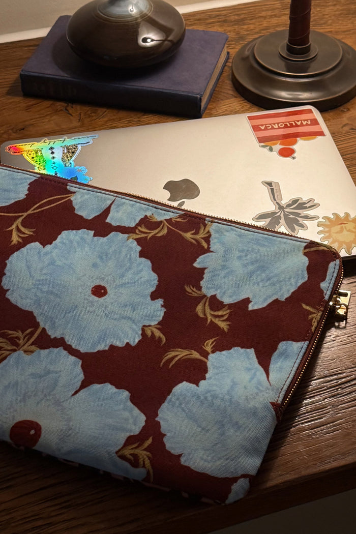 Blue and Burgundy Poppy Laptop Case featuring large blue floral motifs on a burgundy base, placed on a wooden desk.
