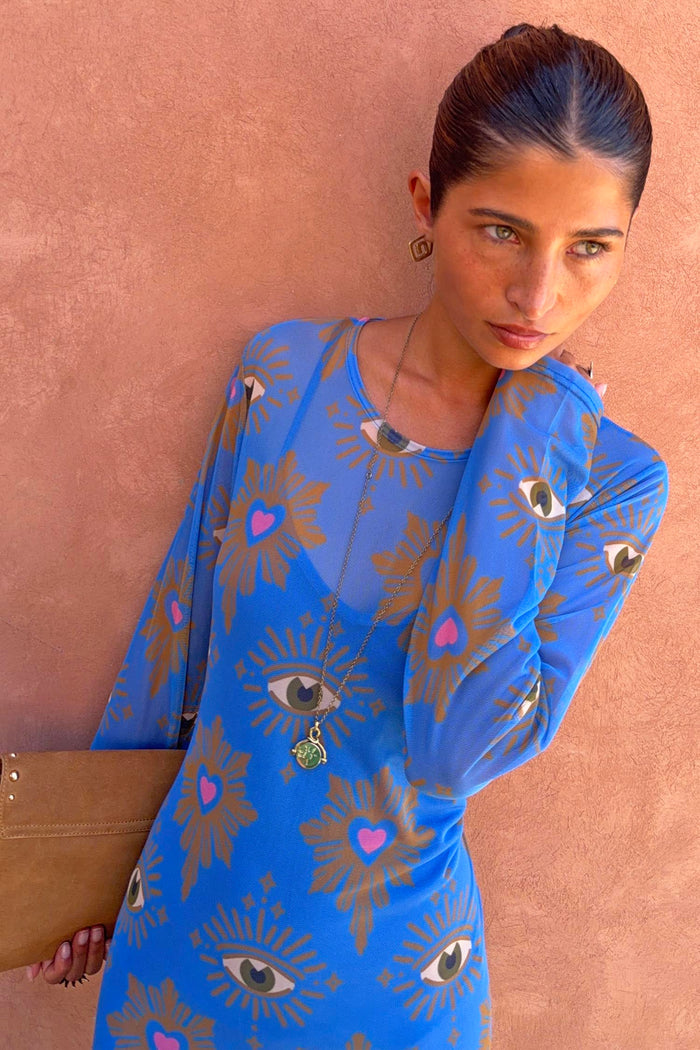 Blue Eye Mesh Petite Dress featuring pink heart and eye motifs, with long sleeves, shown against a terracotta wall.