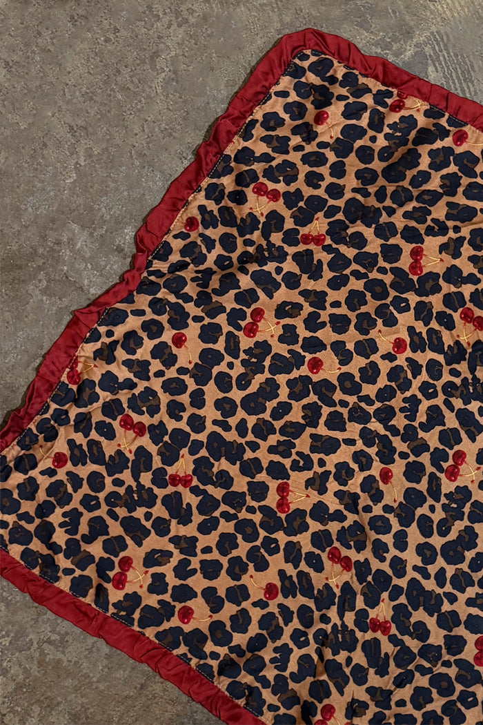 Cherry Leopard Bandana featuring a leopard and cherry print and a deep red ruffle border, shown laid flat.