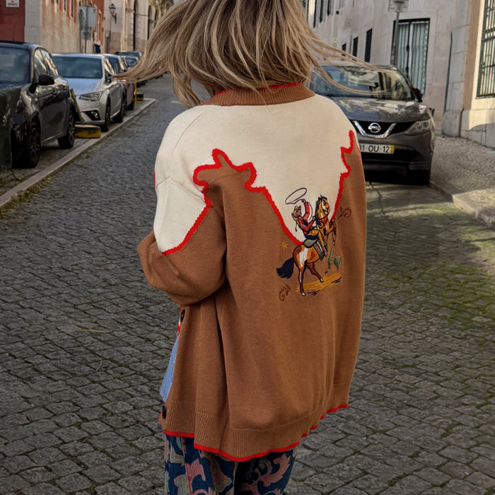 Cowgirl Martha Cardigan in tan and cream knit with an embroidered western motif, styled on a cobbled street.
