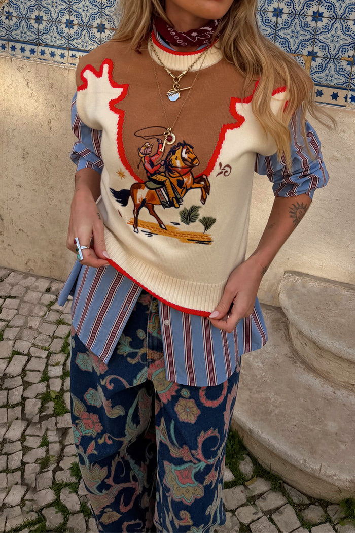 Cowgirl Ro Knitted Tank in cream with an embroidered western motif, styled over a striped shirt and paisley jeans.