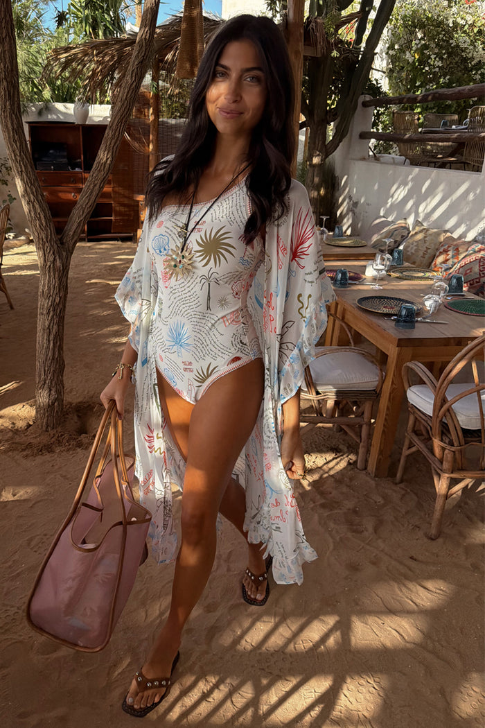 Cream Palma Kimono featuring a colorful Sol De Palma print and frill hem, styled over a matching swimsuit.
