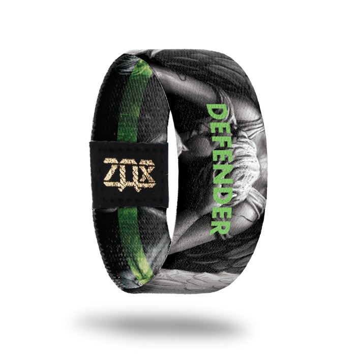Inside design of Defender, grayscale angel in the center of black background with Defender in green transparent text over the angel