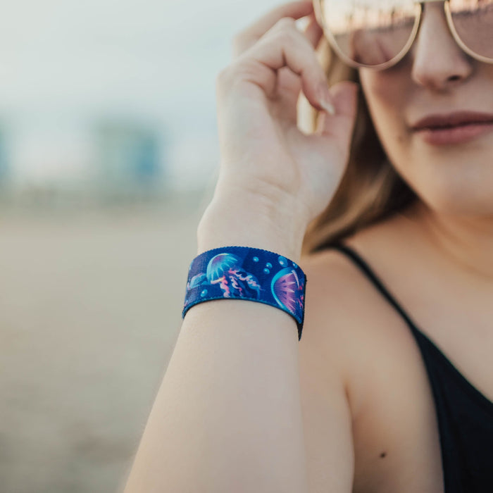 Lifestyle image of woman holding their tan sunglasses while wearing an Electric Bloom