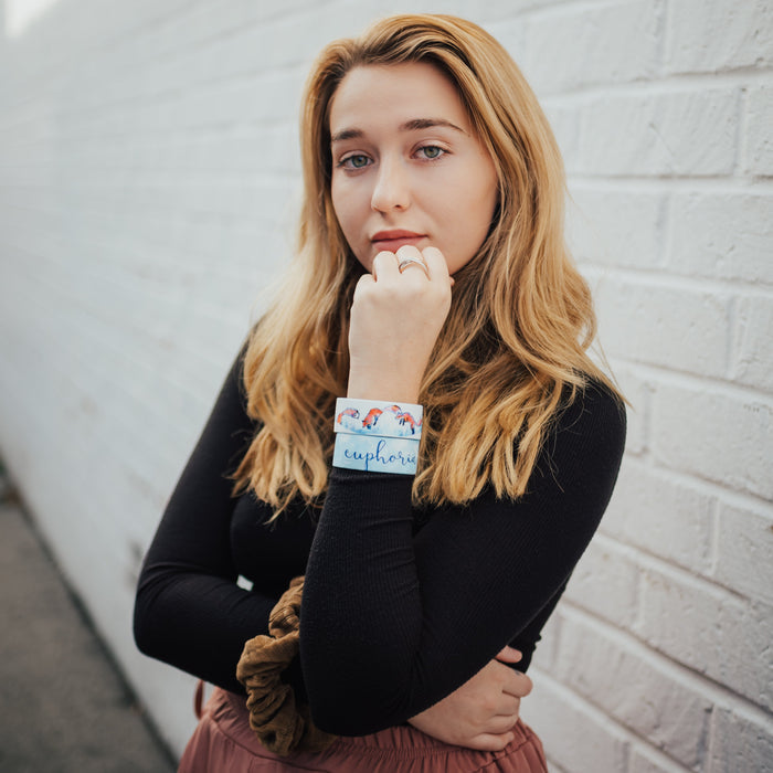 Lifestyle image of model in a standing thoughtful pose and wearing two Euphoria straps