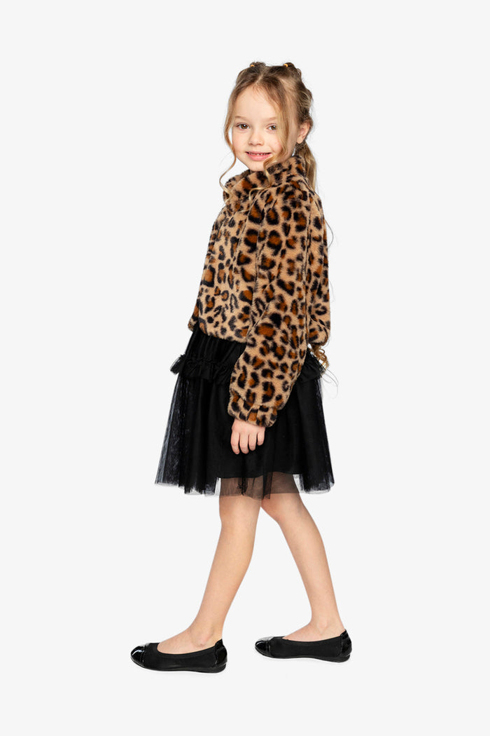 Girl standing in the Deux par Deux brown leopard print faux fur jacket with a black tulle skirt, full-body side view