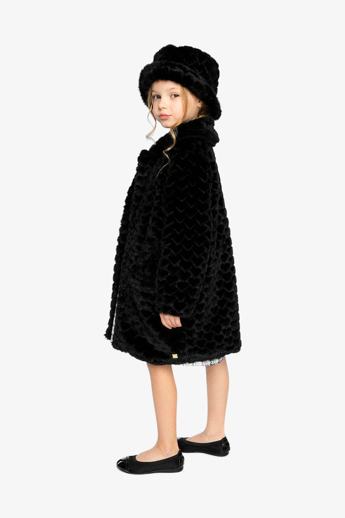 Girl wearing the black faux fur long coat and hat, side view