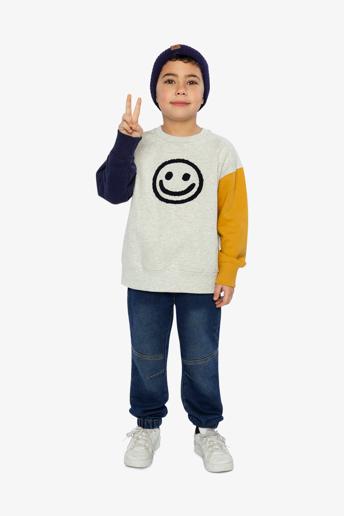 Child wearing Deux par Deux fleece sweatshirt in heather grey, yellow and blue with smiley face graphic, full outfit lookbook view