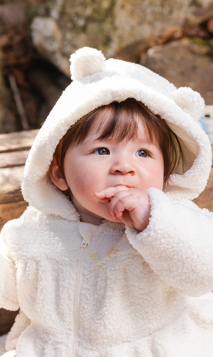 Baby girl wearing the off-white Deux par Deux hooded sherpa jacket with ears on the hood