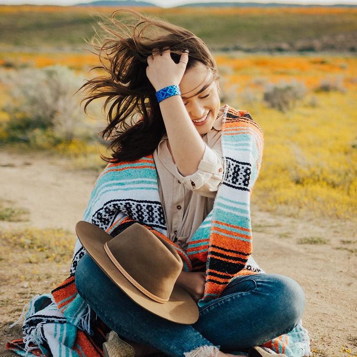 Lifestyle image of someone sitting with their hat in their lap and fixing their hair while wearing I Am Enough