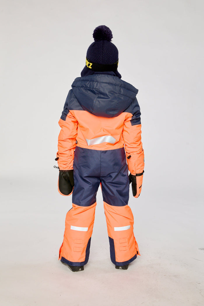 Child wearing the bright orange and blue Deux par Deux TEKNIK one-piece snowsuit, back view