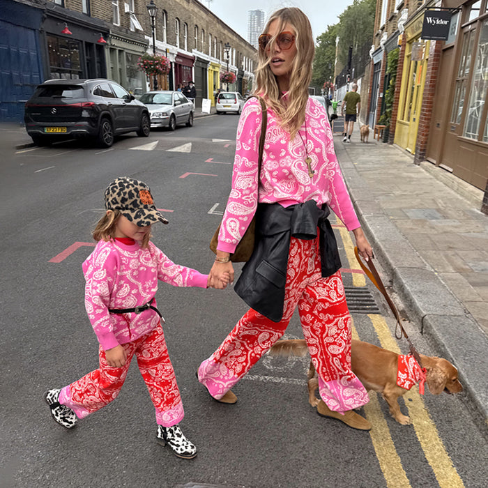 Kids Red and Pink Bandana Knitted Set in a paisley print, worn by a child walking a dog on a London street.