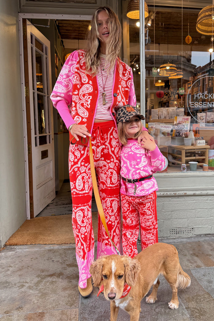 Kids Red and Pink Bandana Knitted Set on a girl and woman standing outside a London shop with a dog.