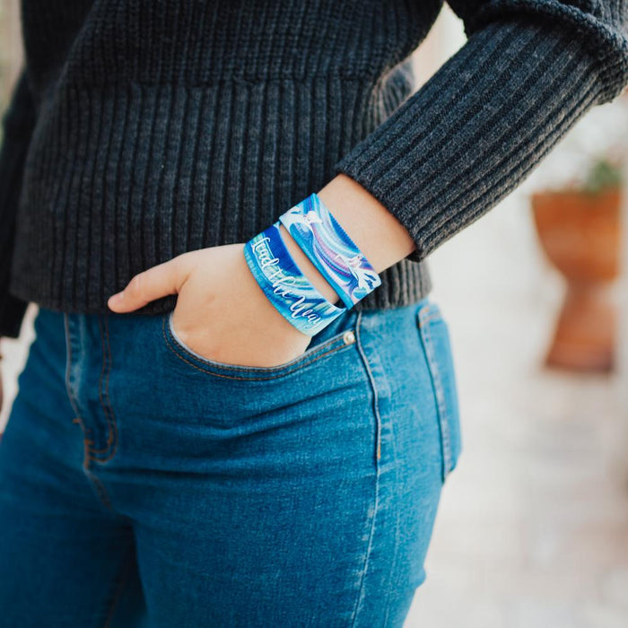Lifestyle close up image of model's hand in their pocket and wearing two Lead The Way straps