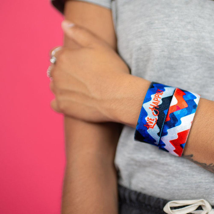Studio image close up of model holding arm and 2 Live Happily on wrist