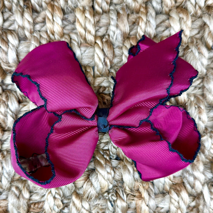 A large magenta pink grosgrain ribbon hair bow with black ruffled trim