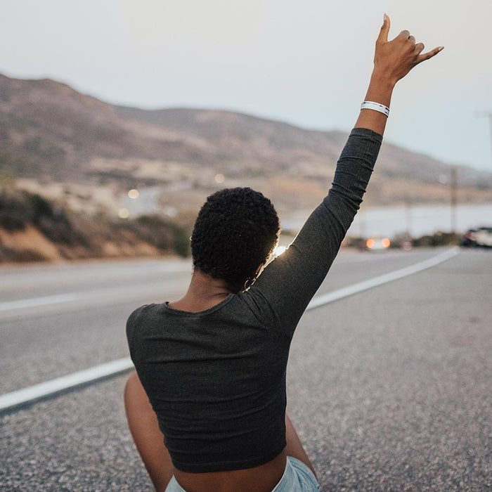 Lifestyle image of someone sitting with their back facing the camera and their hand raised up wearing Never Give Up
