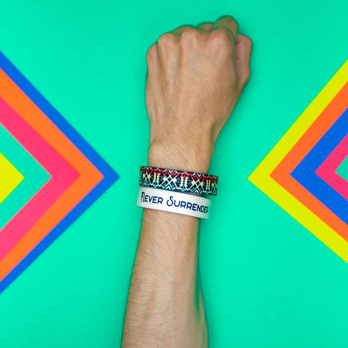 Studio photo of wrist in front of a teal background showing the inside and outside design of never surrender