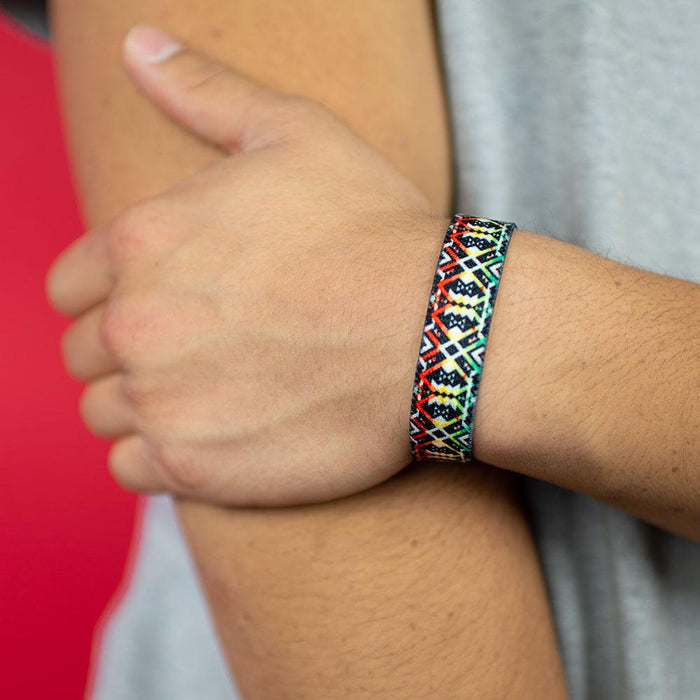 Studio photo up close of a wrist showing the outside design of never surrender a black geometric design with red, green, and yellow accents
