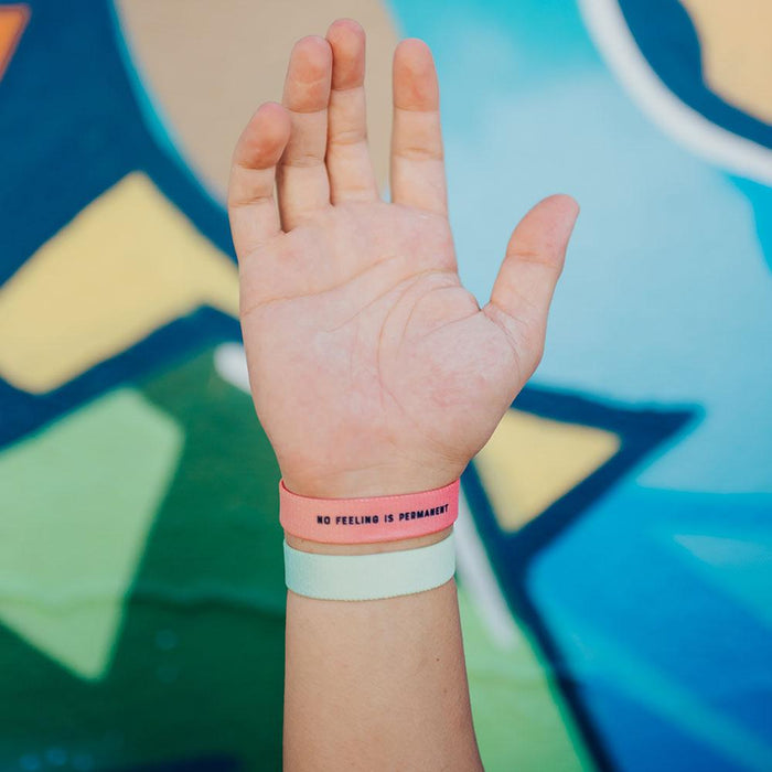 Lifestyle photo up close of wrist showing the inside design of no feeling is permanent above a you are perfect for something single