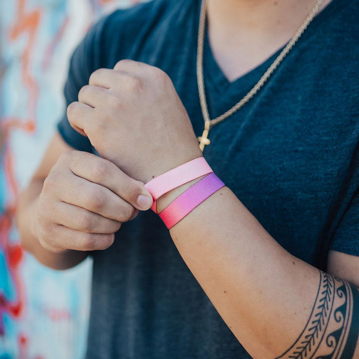 Lifestyle photo of a guy adjusting a no feeling is permanent showing the outside design with a pink to peach gradient above a love yourself single