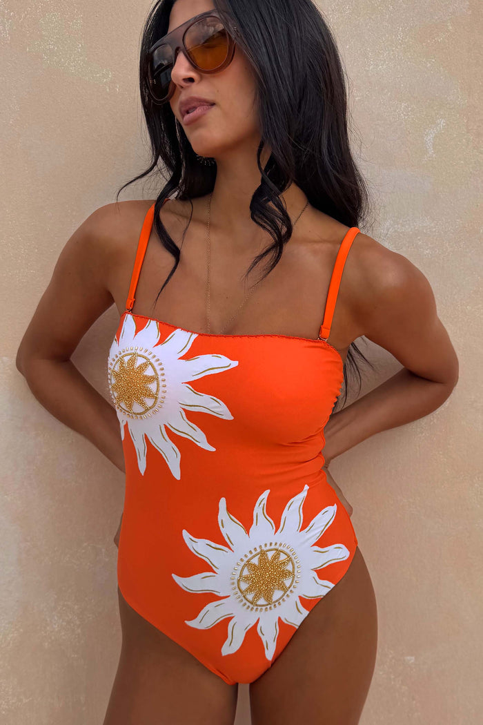 Orange Sun Bandeau Swimsuit with white sun motifs and gold bead embroidery, worn by a model in sunglasses.