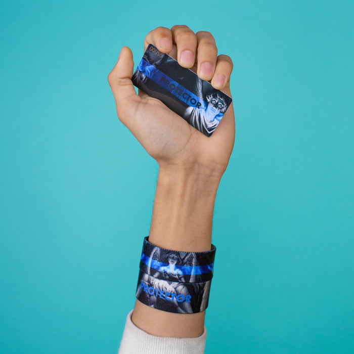 Studio Image of hand holding card that says Protector with 2 Protector straps on their wrist