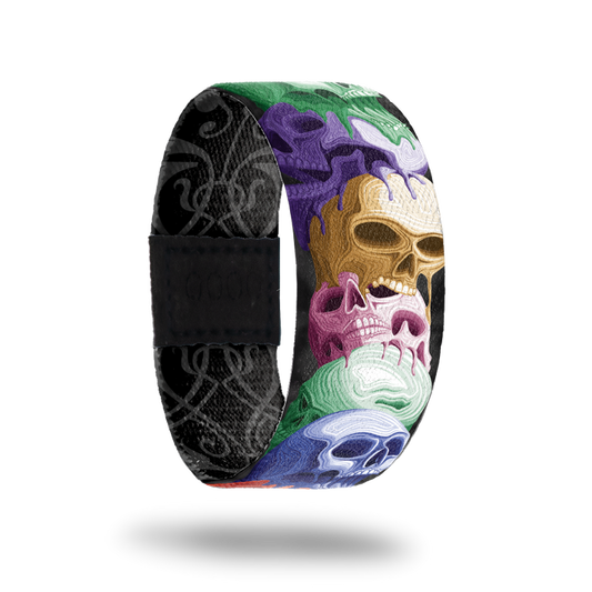 product image of front of wristband named Reflect. The design is a stack of hand drawn skulls in different colors such as purple, gold, pink, blue, and green