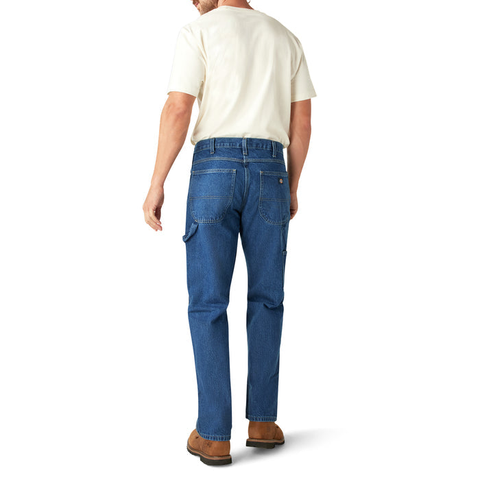 Man wearing cream t-shirt and blue carpenter jeans with side cargo pockets, viewed from behind.