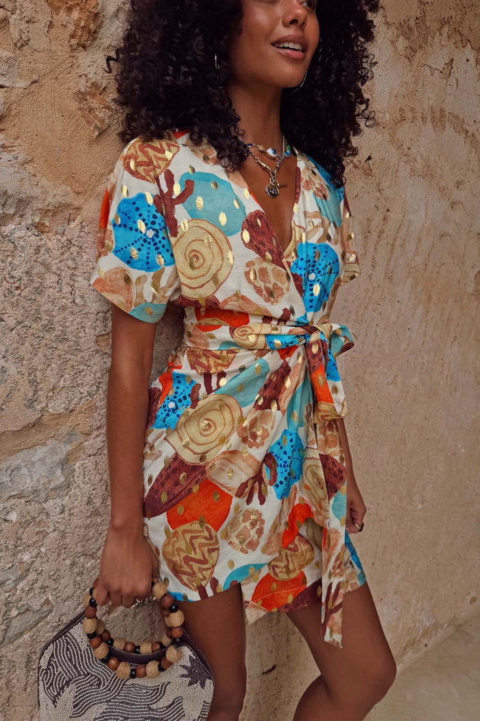 NFD Shell Mini Wrap Dress featuring an abstract shell print with metallic detailing and flutter sleeves.