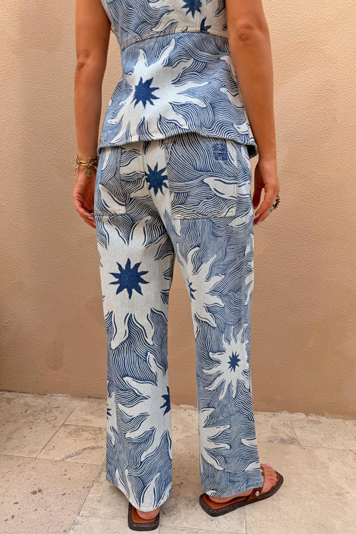 Soleil Jeans in blue denim with oversized sun motifs and wavy lines, shown from the back as a matching co-ord.