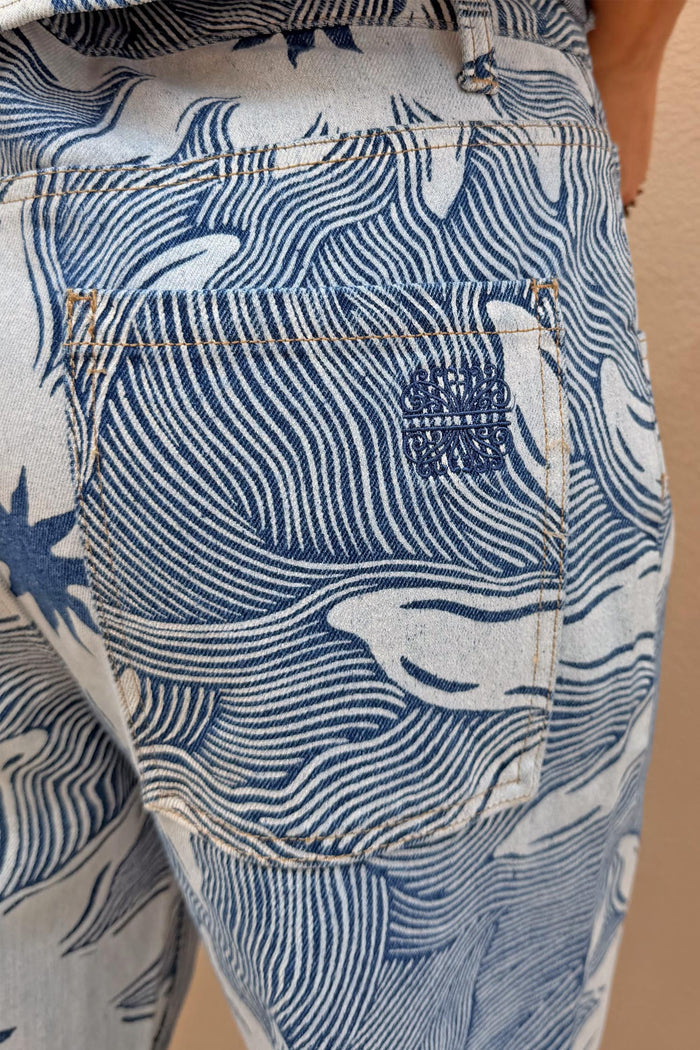 Soleil Jeans back pocket detail featuring a blue and white wavy line print and embroidered sun motif.