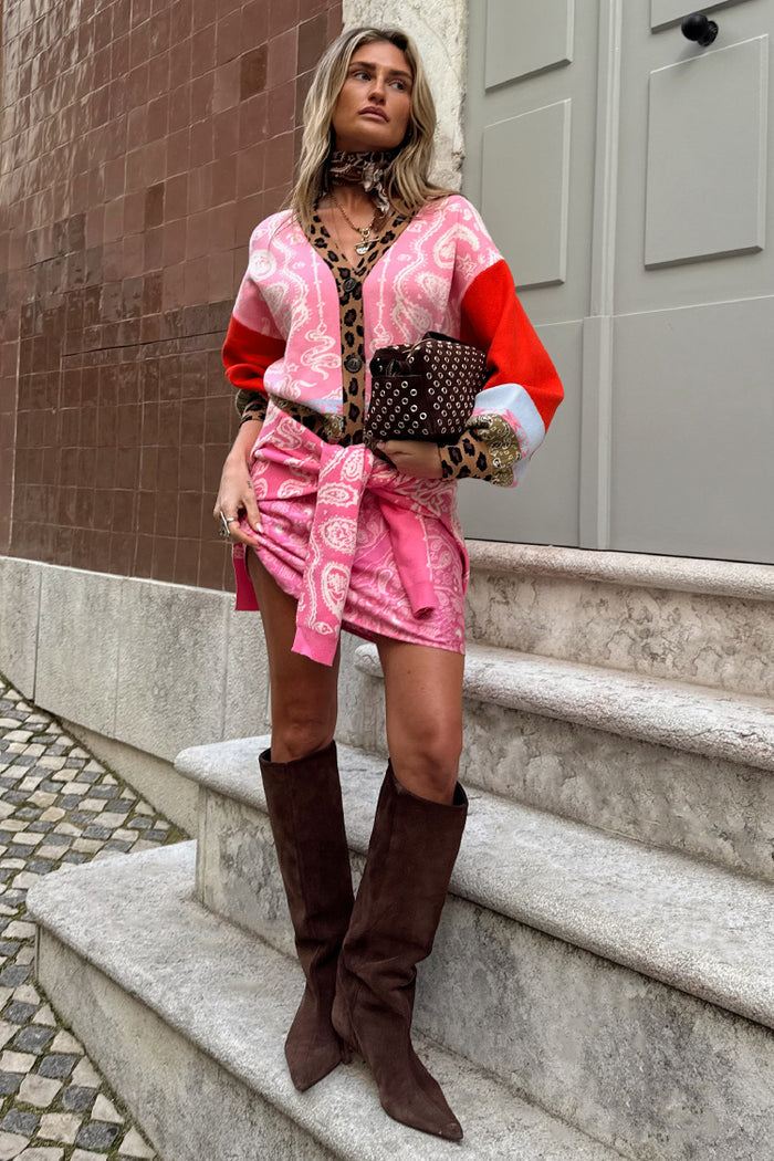 Pink paisley and leopard print Splice Bandana Cardigan with red accents, styled on a model on stone steps.