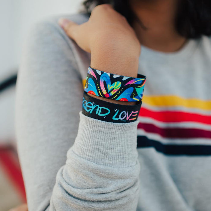 Lifestyle close up image of model's wrist wearing 2 Spread Love straps