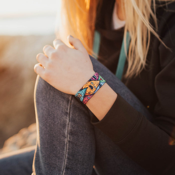 Lifestyle image of hand resting on knee with a Stay Weird on wrist