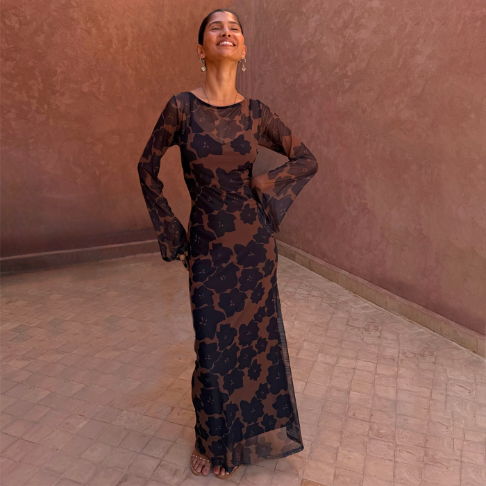 Tan Jaden Floral Mesh Maxi Dress with sheer flared sleeves on a model in a sunlit courtyard.