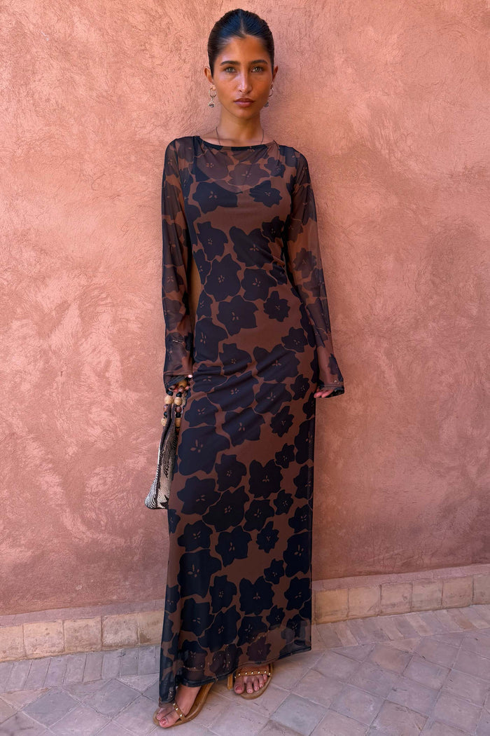 Tan Jaden Floral Mesh Maxi Dress with sheer sleeves and high neck on a model against a pink textured wall.