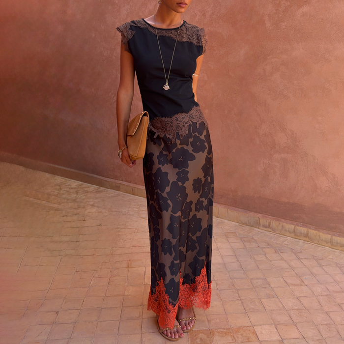 Tan Jaden Floral Maeva Midi Skirt with an orange lace hem, styled with a tan clutch against a terracotta wall.