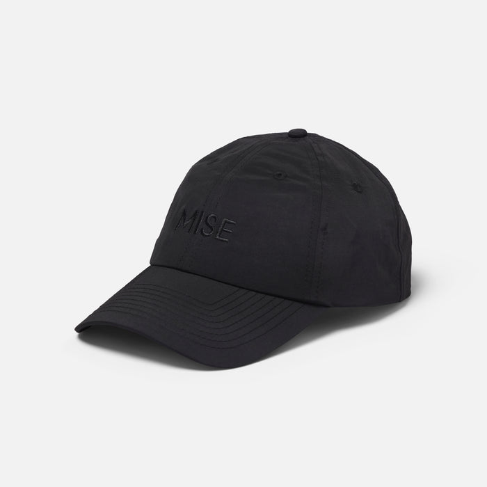 The Dad Cap gallery position 1 showing black 6-panel moisture-wicking cap with subtle MISE embroidery front angle view